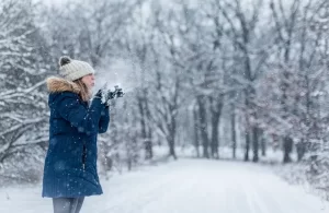 Woman blowing snow out of her hands in the winter