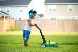 Little boy wearing headphones and pretending to mow the lawn