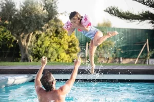 Girl jumping into her father's arms in the pool