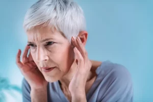 Woman holding her ears because of tinnitus