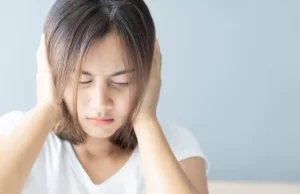 Woman covering her ears because of tinnitus